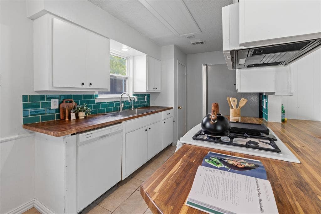 907 Crest Park Drive, Garland, TX 75042 Kitchen featuring wood-finish countertops, white cabinetry, a deep teal subway tile backsplash, a stainless steel sink, and a built-in gas cooktop
