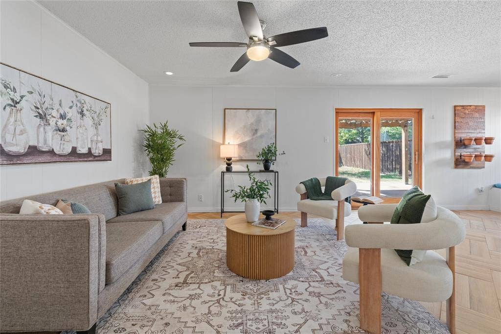 907 Crest Park Drive, Garland, TX 75042 Living area featuring wood-finish flooring in a herringbone pattern, a central ceiling fan with integrated lighting, and wooden-framed glass sliding doors