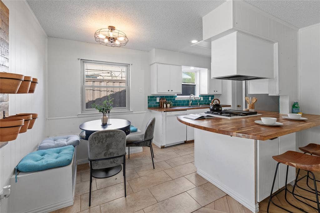 907 Crest Park Drive, Garland, TX 75042 Kitchen featuring a butcher block peninsula with a gas cooktop, teal subway tile backsplash, white cabinetry, and ceramic tile flooring