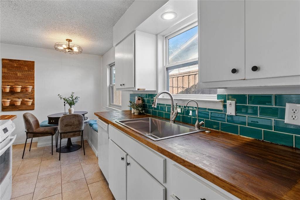 907 Crest Park Drive, Garland, TX 75042 Kitchen featuring wood countertops, white cabinetry, a stainless steel undermount sink with a gooseneck faucet, a teal subway tile backsplash, and tile flooring