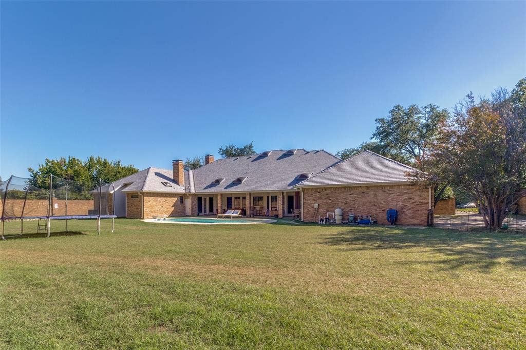 6215 Raintree Court, Dallas, TX 75254 Expansive backyard featuring a brick exterior, a covered patio, an in-ground swimming pool, and mature trees