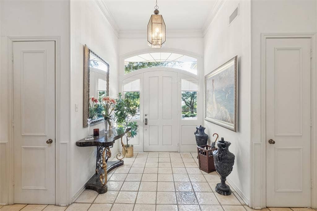 6215 Raintree Court, Dallas, TX 75254 Foyer featuring a high ceiling, ceramic tile flooring, a multi-paneled door with a glass arched transom, and a hanging metal pendant fixture