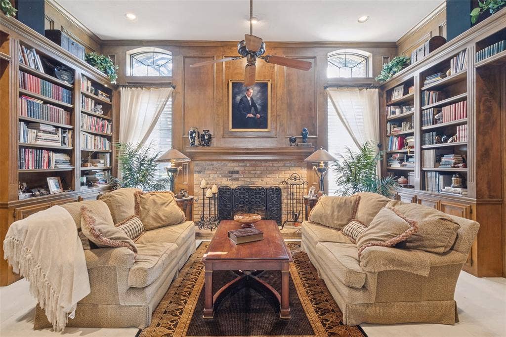 6215 Raintree Court, Dallas, TX 75254 Custom floor-to-ceiling wood cabinetry, expansive built-in bookshelves, brick fireplace surround with heavy mantel, recessed lighting, and dual arched windows