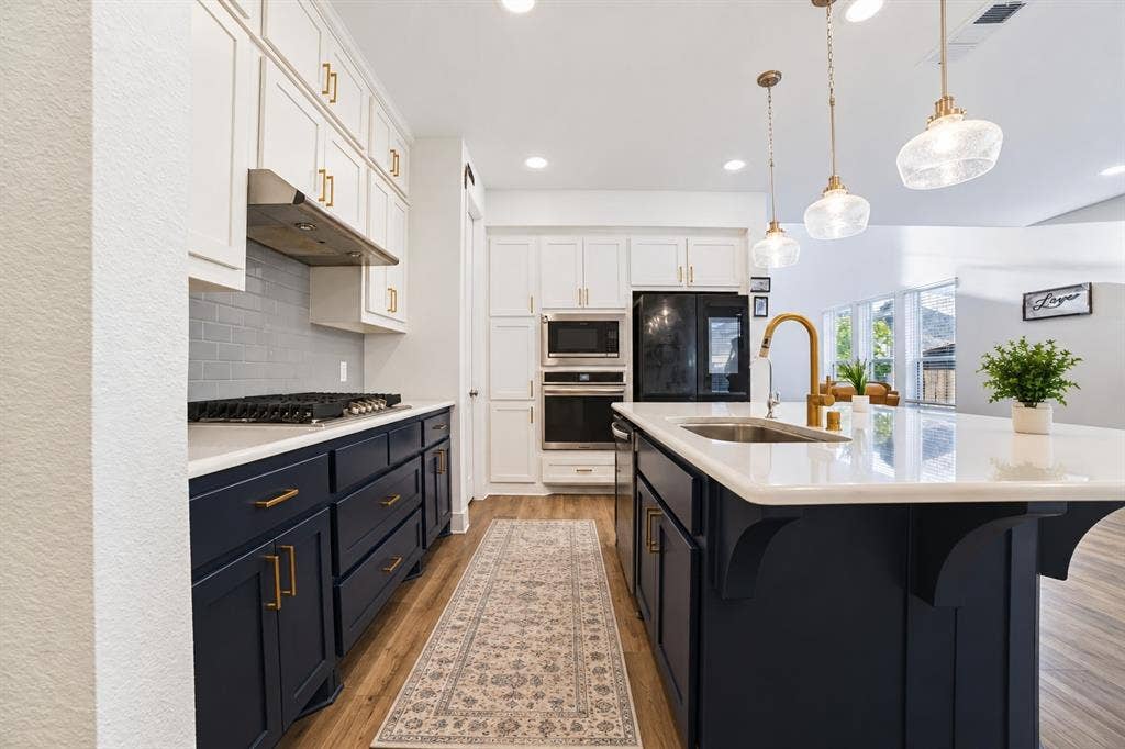2836 Epping Way, Celina, TX 75009 Beautifully kitchen featuring navy cabinetry, gold accents, stainless steel appliances, and a spacious island with quartz countertops.