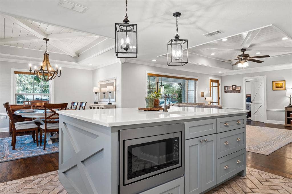 200 Oriental Road, Waco, TX 76710 Center island featuring a stone-surface countertop, built-in microwave, and x-pattern cabinetry, complemented by overhead lantern-style pendant lighting and coffered ceilings