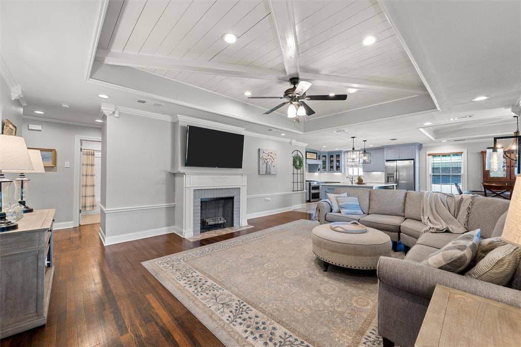 200 Oriental Road, Waco, TX 76710 Tray ceiling with wood-plank detailing and exposed beams, wood-finish flooring, and a fireplace with a custom mantel surround