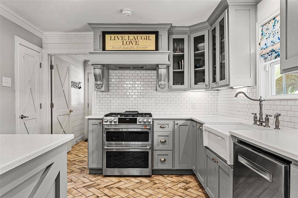 200 Oriental Road, Waco, TX 76710 Kitchen featuring gray shaker-style cabinetry, white subway tile backsplash, stainless steel gas range with a custom range hood, farmhouse sink, and herringbone-patterned brick flooring