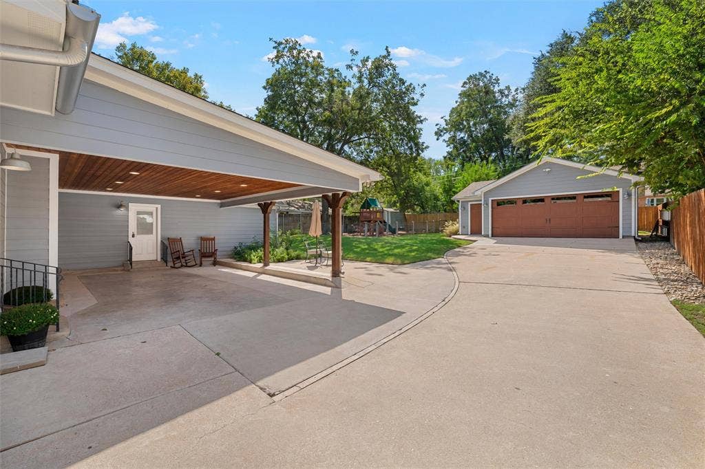 200 Oriental Road, Waco, TX 76710 Covered carport with wood-plank ceiling, detached multi-car garage, concrete driveway, and backyard green space