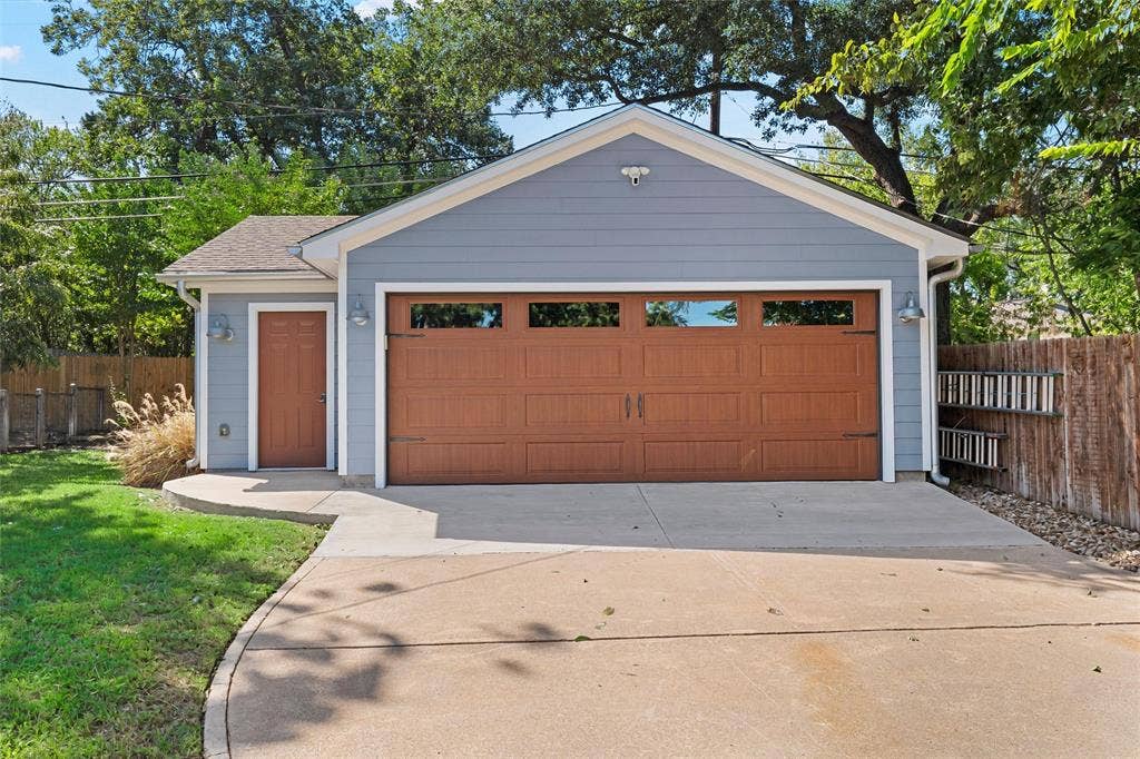 200 Oriental Road, Waco, TX 76710 Detached garage featuring horizontal lap siding, a paneled garage door with glass inserts, a separate service door, and exterior wall-mounted lighting