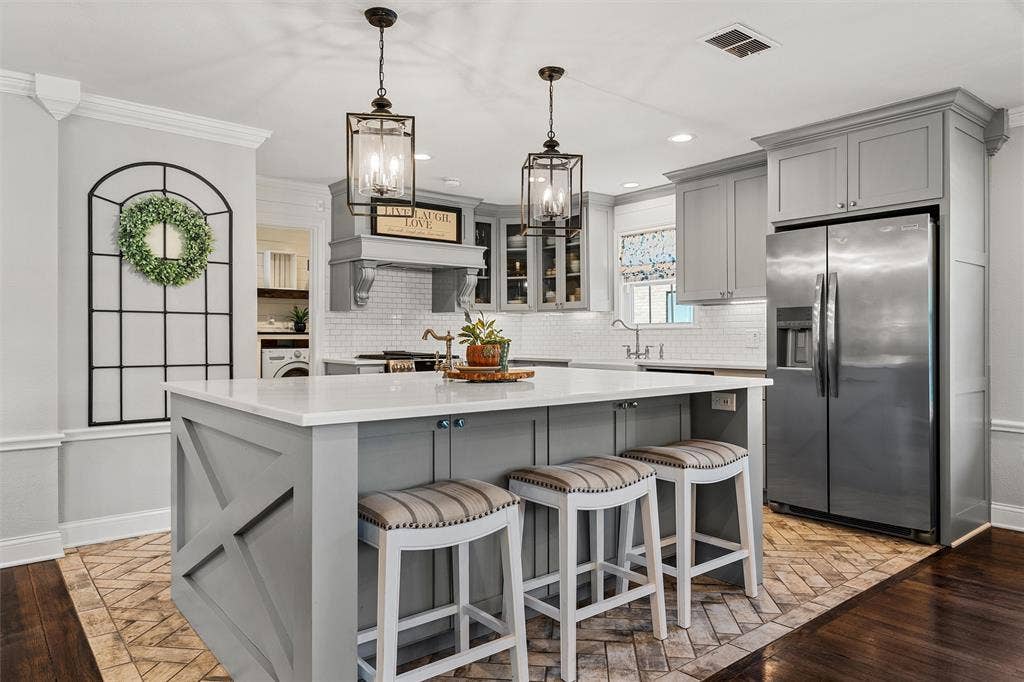 200 Oriental Road, Waco, TX 76710 Kitchen featuring a central island with a solid surface countertop, herringbone-patterned flooring, cabinetry with crown molding, stainless steel refrigerator, and hanging pendant lanterns