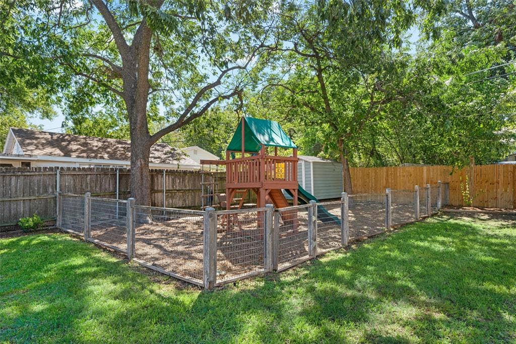 200 Oriental Road, Waco, TX 76710 Fenced backyard featuring wood-post wire mesh enclosure, mature tree canopy, and detached storage structure