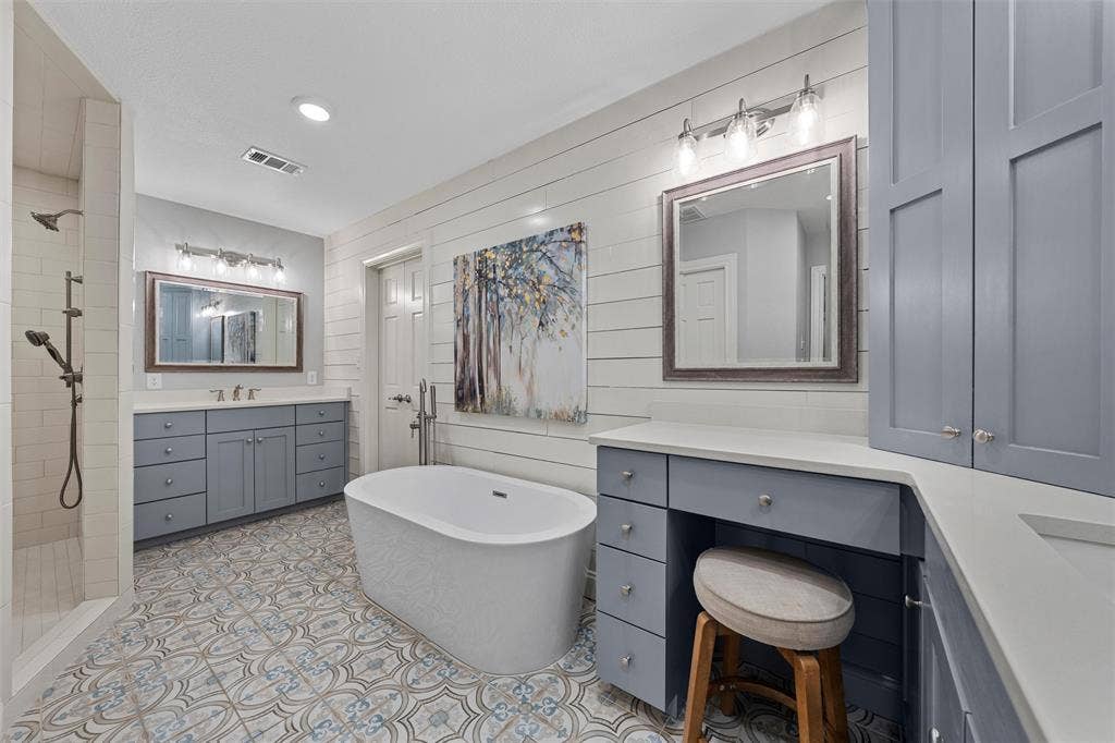 200 Oriental Road, Waco, TX 76710 Freestanding soaking tub, dual-sink vanity with light-colored countertops, shiplap wall accents, patterned tile flooring, and walk-in shower with vertical tile surround