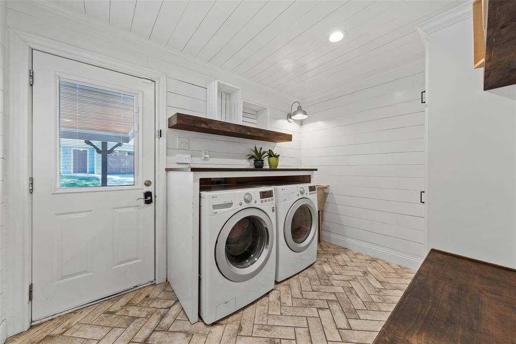 200 Oriental Road, Waco, TX 76710 Laundry room featuring herringbone-patterned tile flooring, horizontal plank walls, a built-in wood countertop, wall-mounted gooseneck lighting, and a solid-core exterior door with an inset glass pane