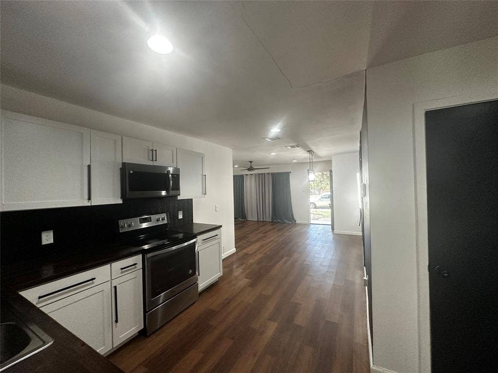 4808 Sandra Lynn Drive, Mesquite, TX 75150 Kitchen featuring white shaker-style cabinetry, dark countertops, a stainless steel range and microwave, and wood-finish flooring