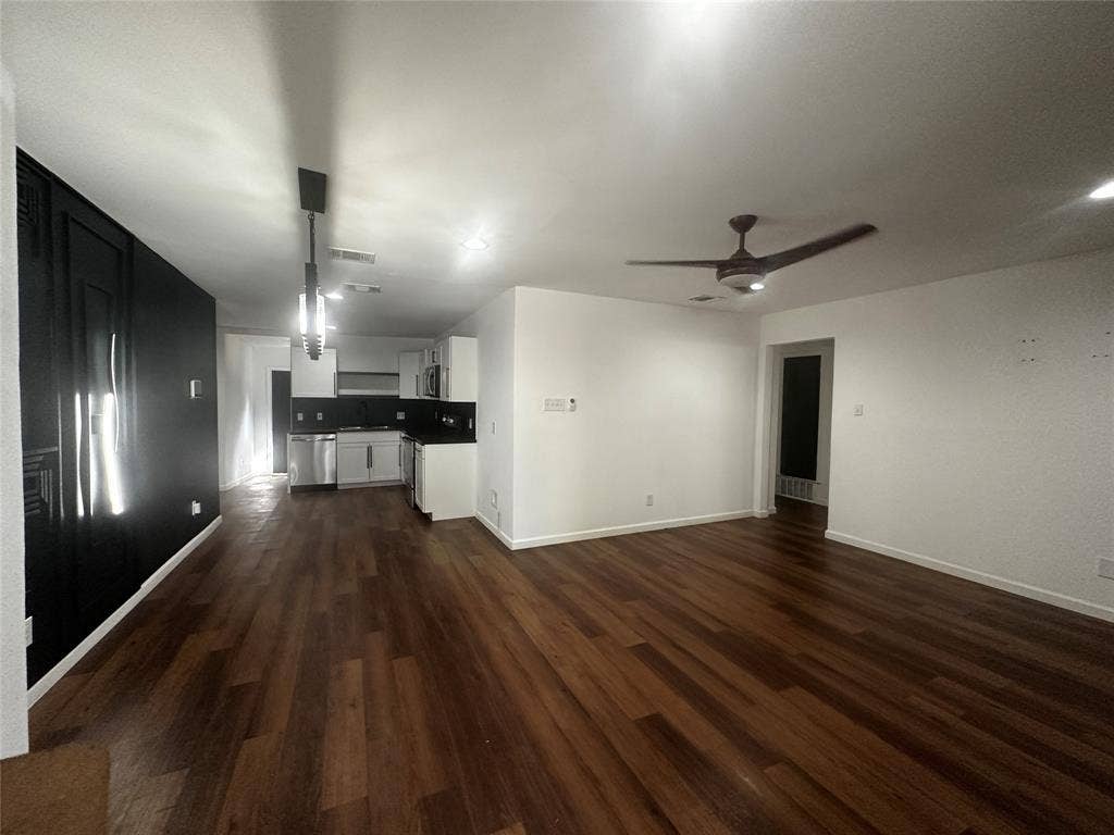 4808 Sandra Lynn Drive, Mesquite, TX 75150 Open-concept interior featuring wood-finish flooring, a dark accent wall, a ceiling fan, recessed lighting, and a kitchen equipped with stainless steel appliances