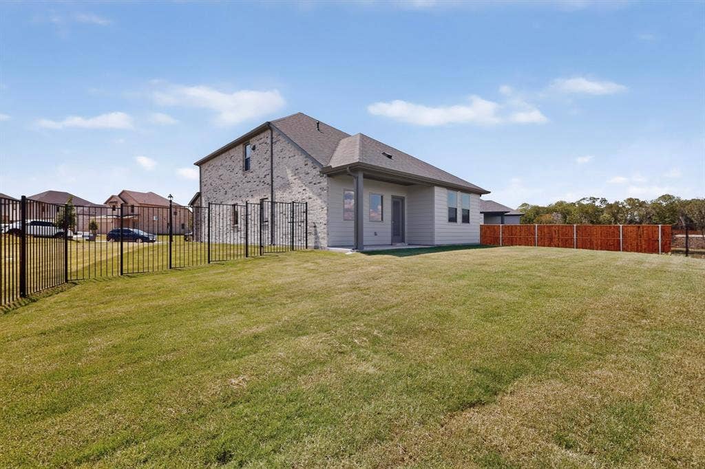 6001 Kaitlynn Drive, Princeton, TX 75071 Rear exterior featuring a brick and siding facade, a covered patio, and a fenced-in lawn with metal and wood privacy fencing