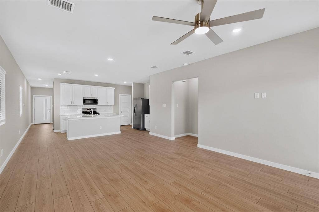6001 Kaitlynn Drive, Princeton, TX 75071 Open-concept interior featuring wood-finish flooring, recessed lighting, a modern ceiling fan, and white cabinetry