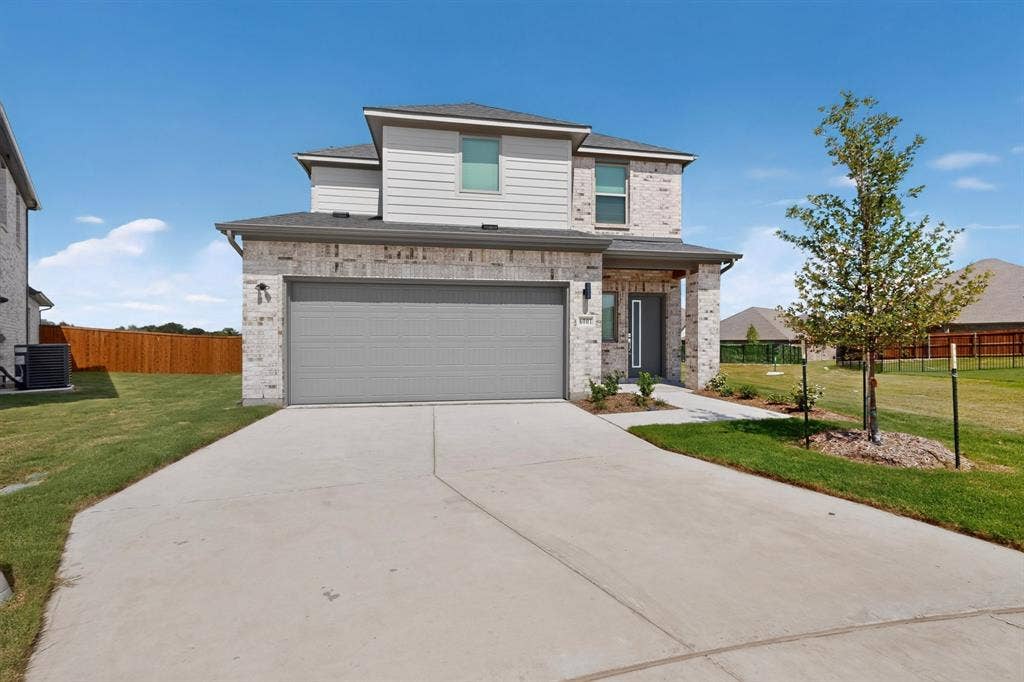 6001 Kaitlynn Drive, Princeton, TX 75071 Two-story exterior featuring a light-toned brick and horizontal siding facade, concrete driveway, attached garage, and covered entryway