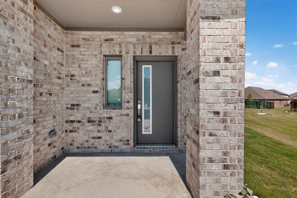 6001 Kaitlynn Drive, Princeton, TX 75071 Covered entry featuring a brick facade, recessed lighting, and a modern door with a vertical glass pane