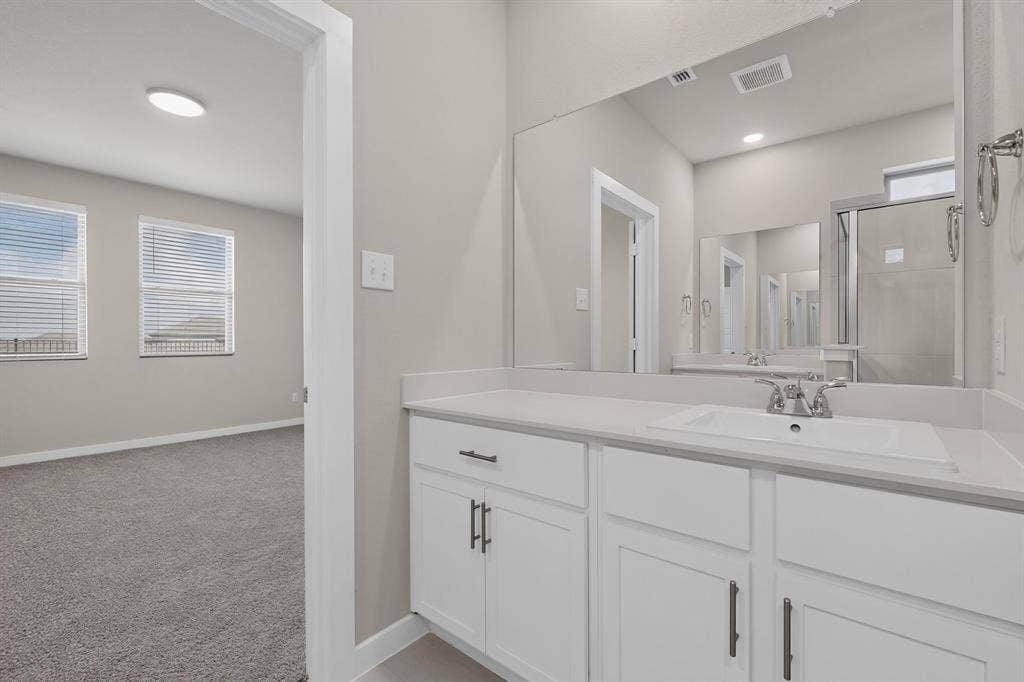 6001 Kaitlynn Drive, Princeton, TX 75071 Bathroom vanity featuring white cabinetry, dark hardware, and an integrated countertop sink with a chrome faucet
