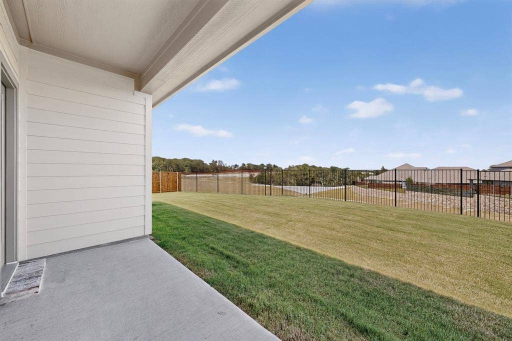 6001 Kaitlynn Drive, Princeton, TX 75071 Covered concrete patio with horizontal siding, large grass lawn, and metal perimeter fencing