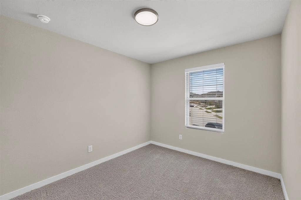 6001 Kaitlynn Drive, Princeton, TX 75071 Neutral-toned interior room featuring wall-to-wall carpeting, a single-pane window with horizontal blinds, and a central flush-mount ceiling light fixture