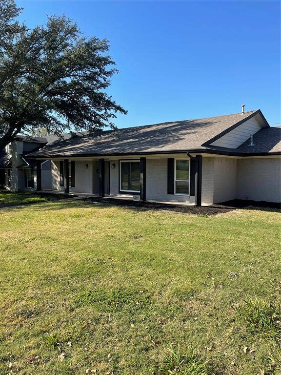 1423 Northridge Drive, Carrollton, TX 75006 Single-story residence featuring a painted brick exterior, dark-trimmed windows, a covered front porch with support pillars, a composition shingle roof, and mature trees
