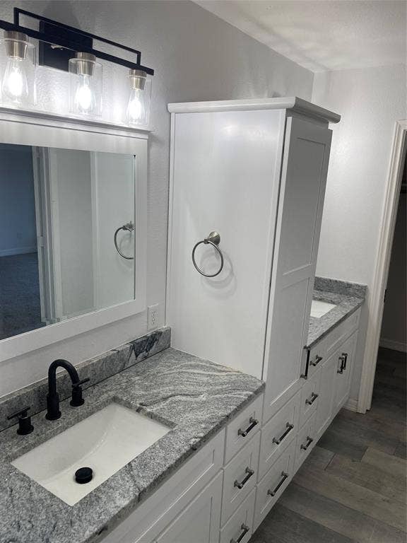 1423 Northridge Drive, Carrollton, TX 75006 Bathroom vanity featuring white shaker-style cabinetry, stone-patterned countertops, undermount rectangular sinks, matte black widespread faucets, and a three-light fixture
