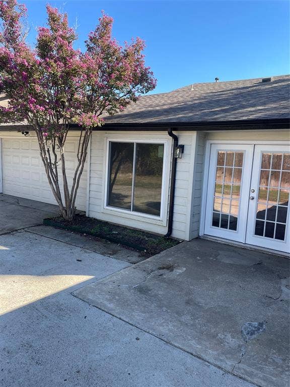 1423 Northridge Drive, Carrollton, TX 75006 Exterior featuring light-colored horizontal siding, dual French doors with glass panes, a multi-car garage, and a large flowering crape myrtle tree