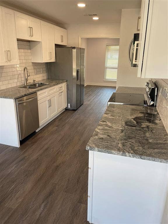 1423 Northridge Drive, Carrollton, TX 75006 Kitchen featuring white shaker-style cabinetry, patterned stone countertops, stainless steel appliances, subway tile backsplash, and wood-finish flooring