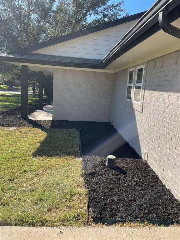 1423 Northridge Drive, Carrollton, TX 75006 Exterior featuring a neutral-toned brick facade, dark-toned trim, a concrete porch, and landscaped mulch beds
