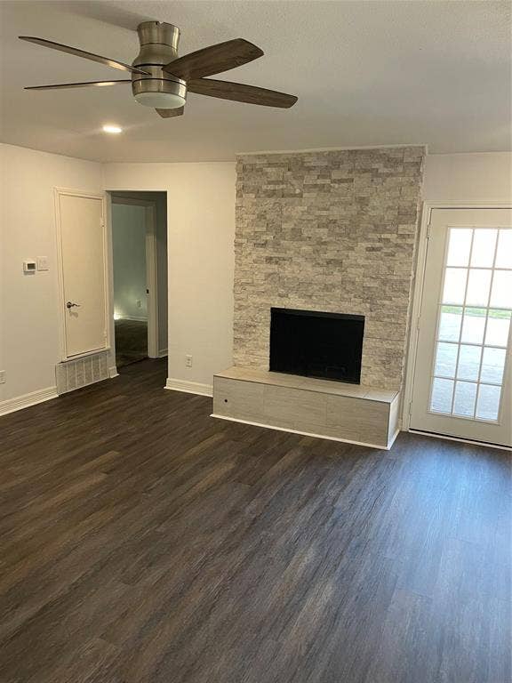1423 Northridge Drive, Carrollton, TX 75006 Fireplace featuring a floor-to-ceiling stacked stone surround, wood-finish flooring, a modern multi-blade ceiling fan, and a glass-paneled door