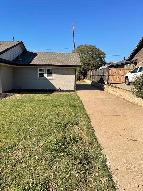 1423 Northridge Drive, Carrollton, TX 75006 Exterior elevation featuring masonry siding, asphalt shingle roofing, a concrete driveway, and a stone retaining wall
