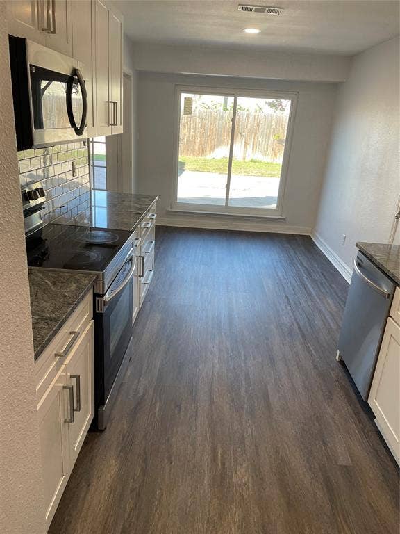 1423 Northridge Drive, Carrollton, TX 75006 Kitchen featuring white shaker cabinetry, stone-finish countertops, subway tile backsplash, stainless steel appliances, and wood-finish flooring with sliding glass door access to the exterior