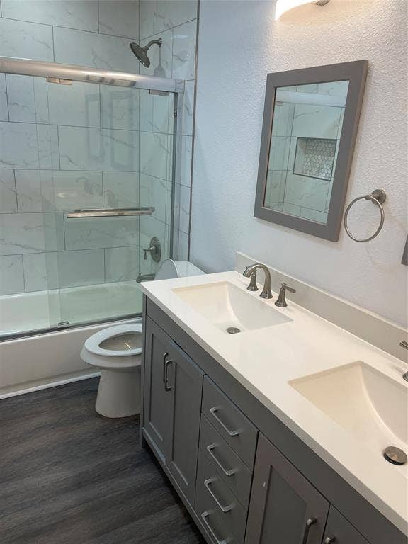 1423 Northridge Drive, Carrollton, TX 75006 Double vanity featuring quartz countertops, undermount sinks, grey shaker-style cabinetry, and a shower-tub combination with tiled surround and glass sliding doors