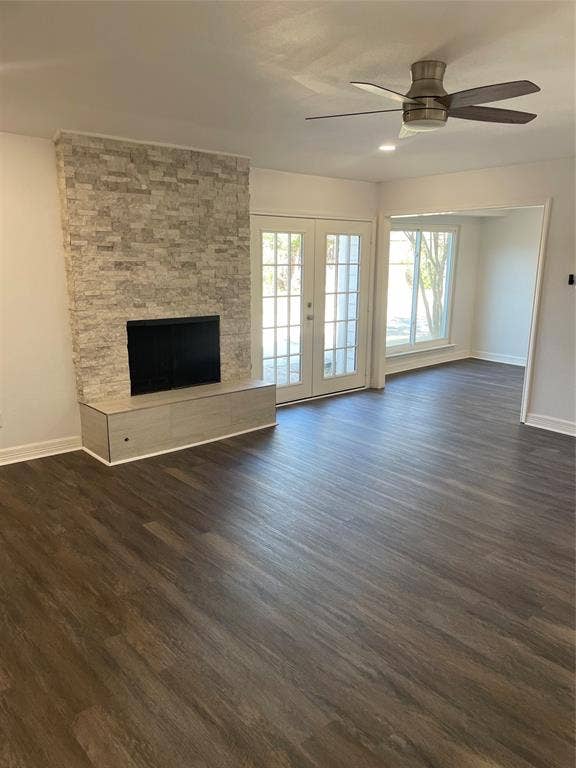 1423 Northridge Drive, Carrollton, TX 75006 Stacked stone fireplace with a built-in hearth, wood-finish flooring, double glass-paneled doors, and a ceiling-mounted fan
