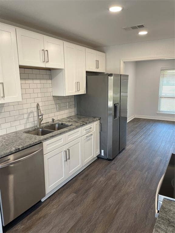 1423 Northridge Drive, Carrollton, TX 75006 Kitchen featuring white shaker-style cabinetry, stone-patterned countertops, a subway tile backsplash, stainless steel appliances, and wood-finish flooring