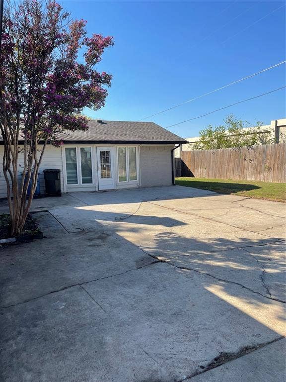 1423 Northridge Drive, Carrollton, TX 75006 Exterior space featuring a concrete patio, wood fencing, and a mature flowering tree