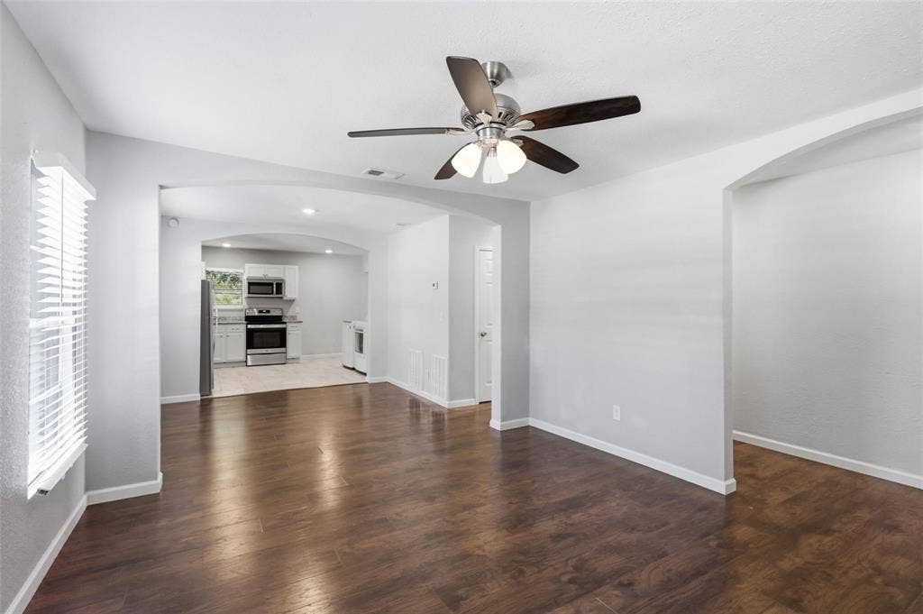1227 Wilbur Street, Dallas, TX 75224 Interior featuring wood-finish flooring, arched doorways, a ceiling fan with integrated lighting, and horizontal blinds