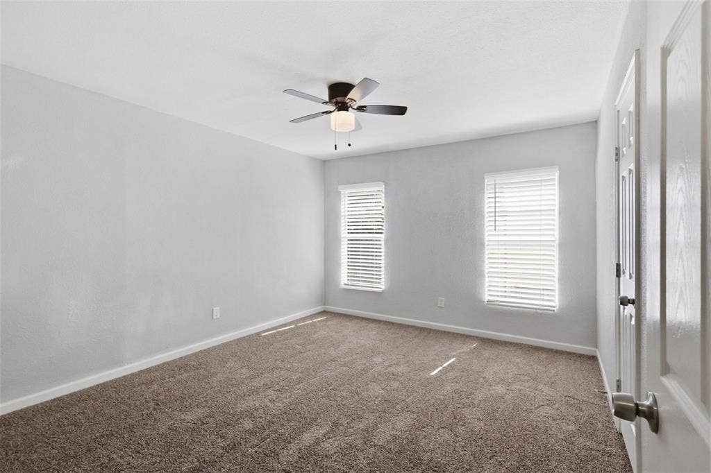 1227 Wilbur Street, Dallas, TX 75224 Neutral-toned interior space featuring carpeting, two windows with installed blinds, and a centrally mounted ceiling fan