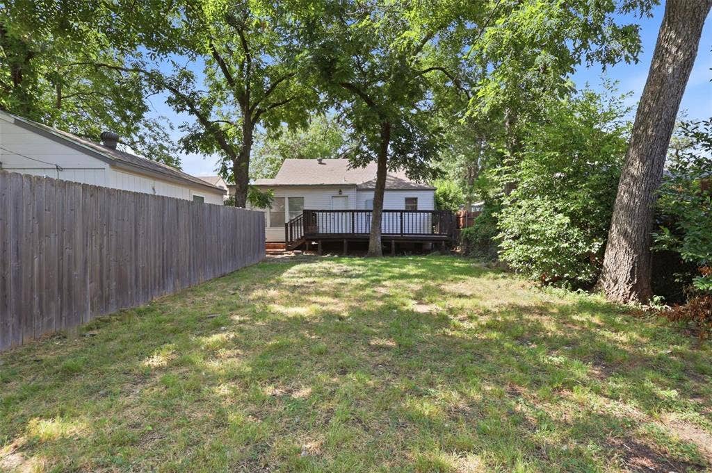 1227 Wilbur Street, Dallas, TX 75224 Backyard featuring a wood deck, vertical board fencing, and mature trees