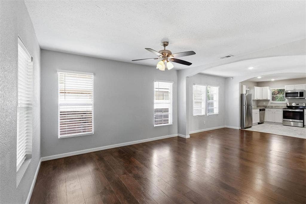 1227 Wilbur Street, Dallas, TX 75224 Wood-finish flooring, neutral wall tones, multi-light ceiling fan, multiple windows with integrated blinds, and arched architectural detailing