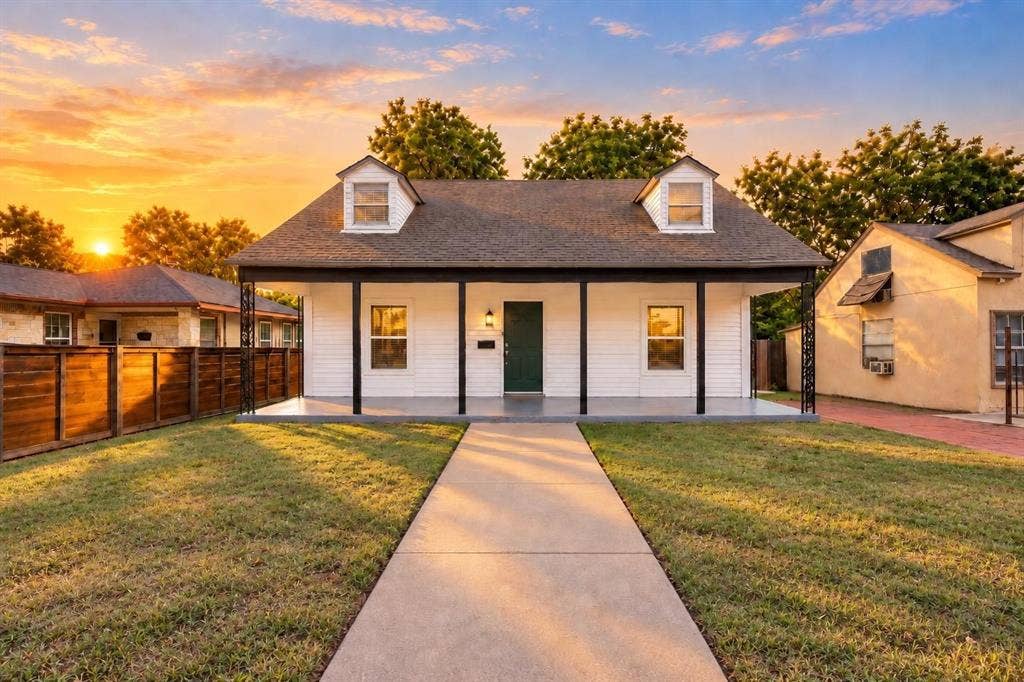 1227 Wilbur Street, Dallas, TX 75224 Exterior featuring white siding, a covered front porch with iron support columns, dual roof dormers, and a concrete walkway