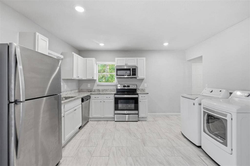 1227 Wilbur Street, Dallas, TX 75224 Kitchen featuring white shaker-style cabinetry, stone-finish countertops, stainless steel appliances, and tile flooring