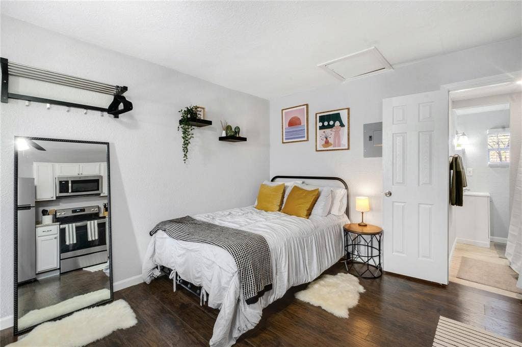 1227 Wilbur Street, Dallas, TX 75224 Wood-finish flooring, two wall-mounted floating shelves, and a six-panel interior door