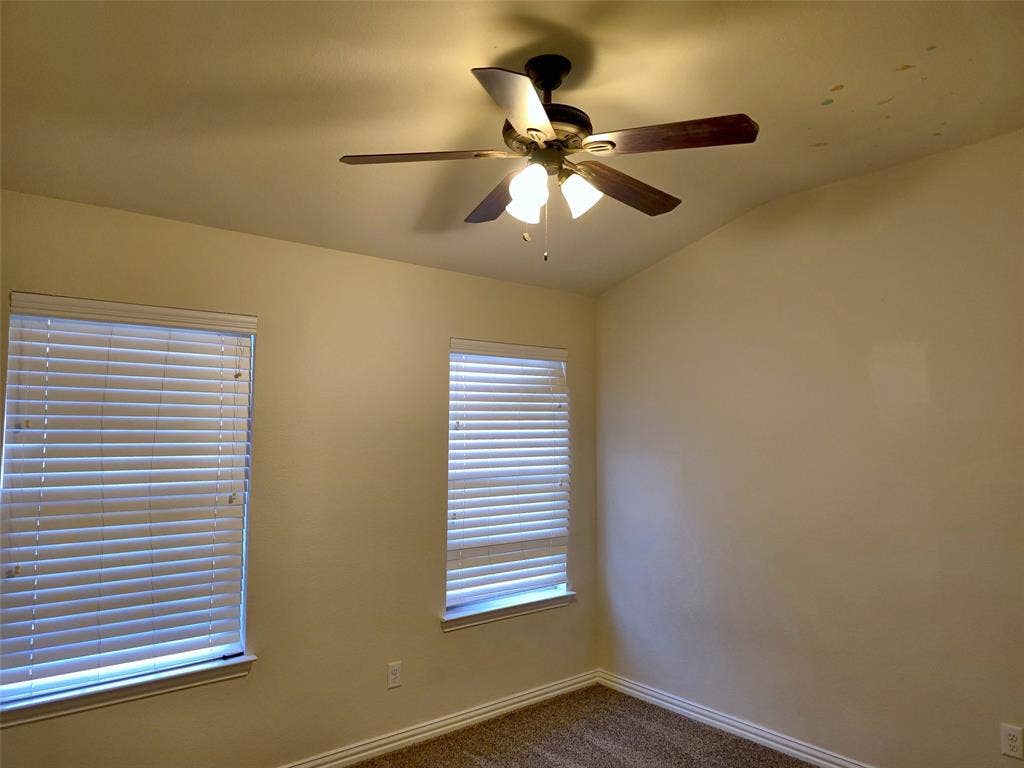 1504 Fox Run Drive, Irving, TX 75063 Interior room featuring neutral wall tones, multi-blade ceiling fan with integrated lighting, and two windows outfitted with horizontal blinds
