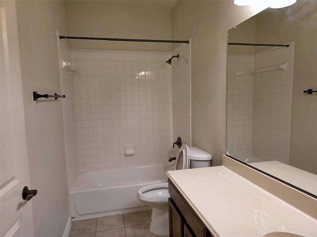1504 Fox Run Drive, Irving, TX 75063 Full-width vanity with countertop, wall-mounted mirror, tub-shower combination with tile surround, and neutral floor tile