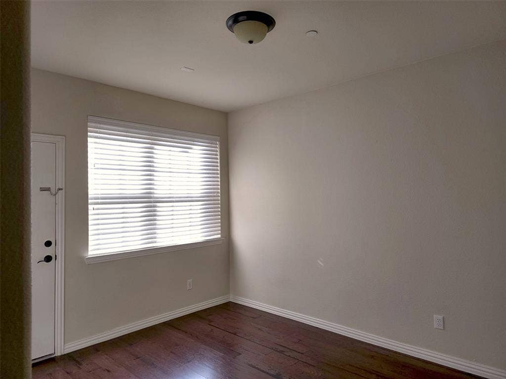1504 Fox Run Drive, Irving, TX 75063 Room featuring wood-finish flooring, a neutral wall palette, large window with horizontal blinds, and flush-mount overhead lighting
