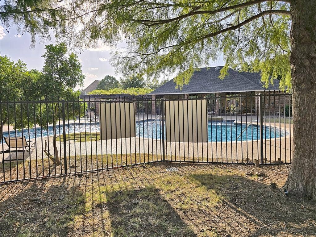 1504 Fox Run Drive, Irving, TX 75063 Swimming pool with a paved deck, enclosed by a black metal fence, featuring a pergola and brick-exterior structures