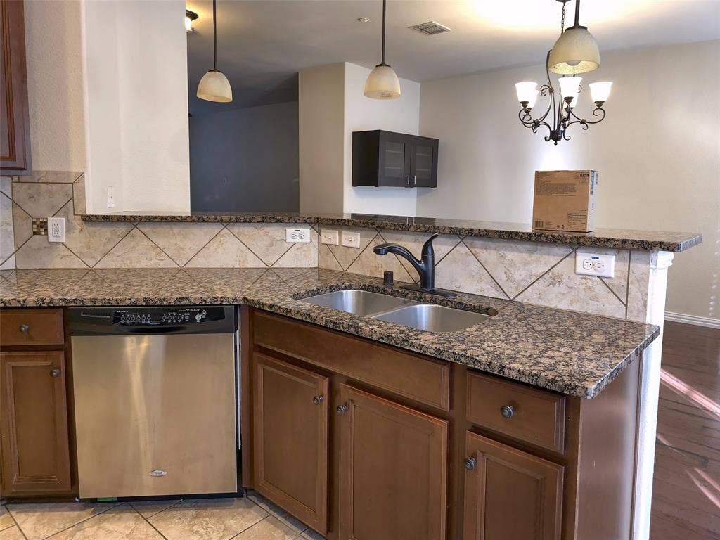 1504 Fox Run Drive, Irving, TX 75063 Kitchen featuring stone-finish countertops, diagonal tile backsplash, stainless steel dishwasher, dual-basin under-mount sink with matte black faucet, and wood-finish cabinetry